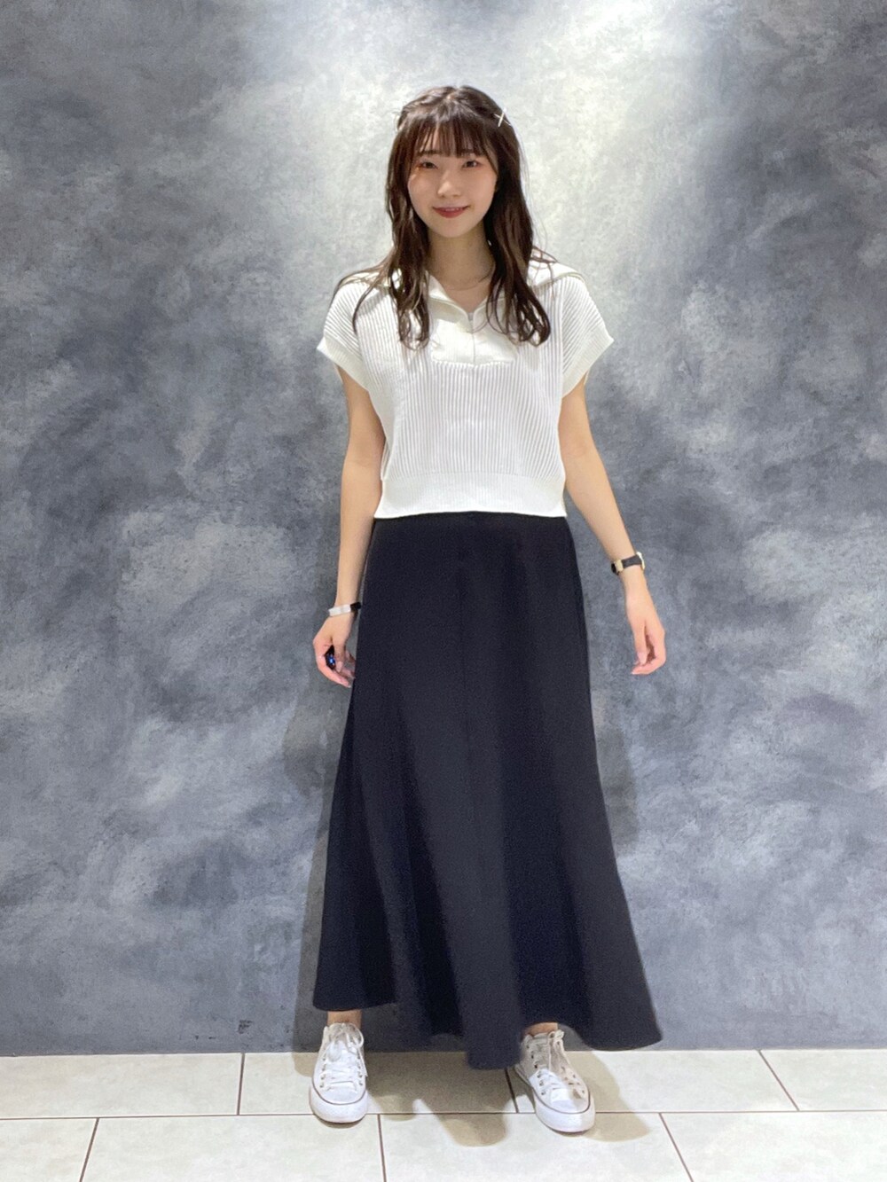 ホワイト系のニット/セーター、ブラック系のスカート、ホワイト系のスニーカーを着用したレディースの夏コーディネートの2枚目の写真