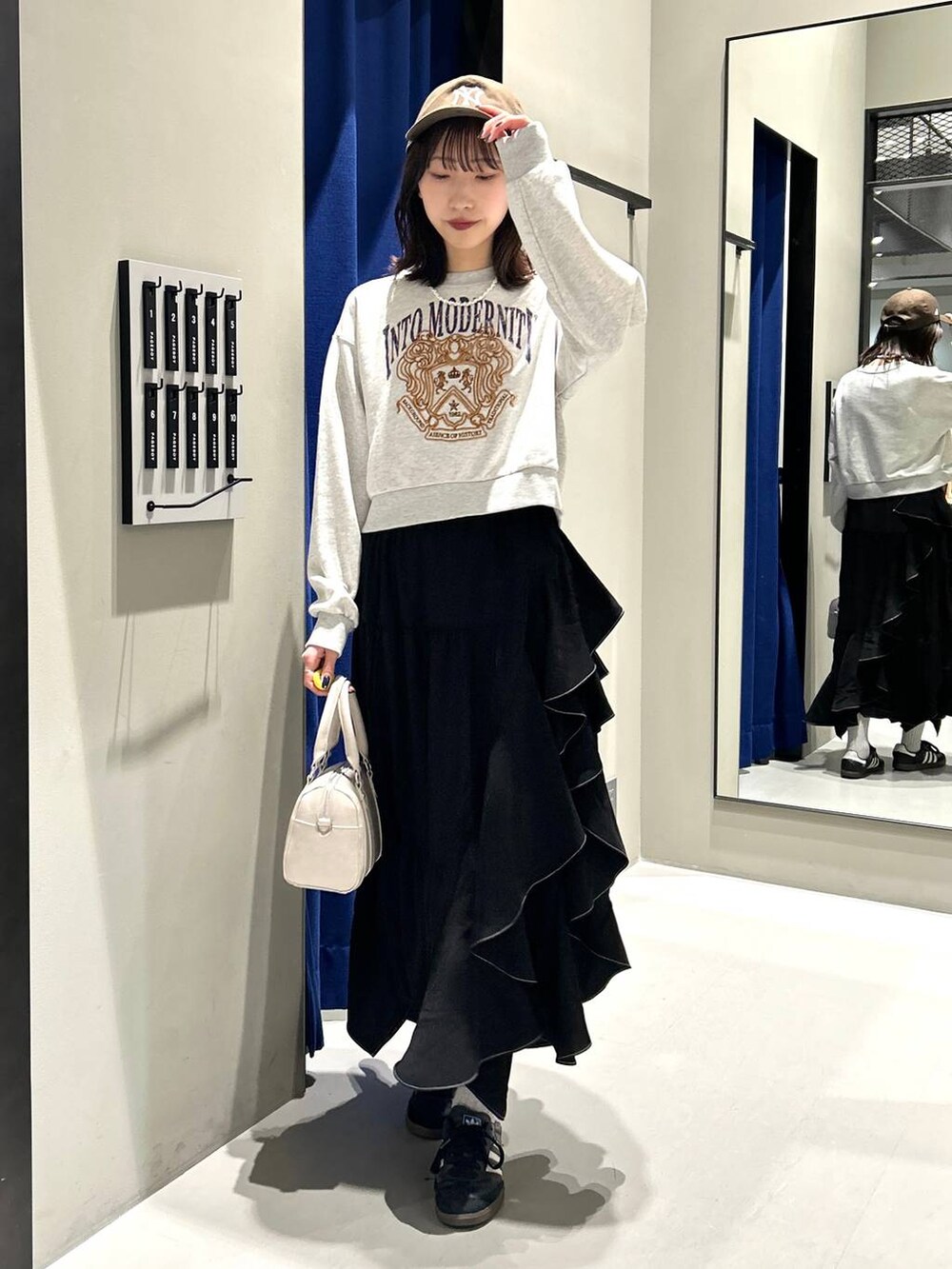 ブラック系のスカート、ホワイト系のボストンバッグ、グレー系のスウェットを着用したレディースの冬コーディネートの3枚目の写真