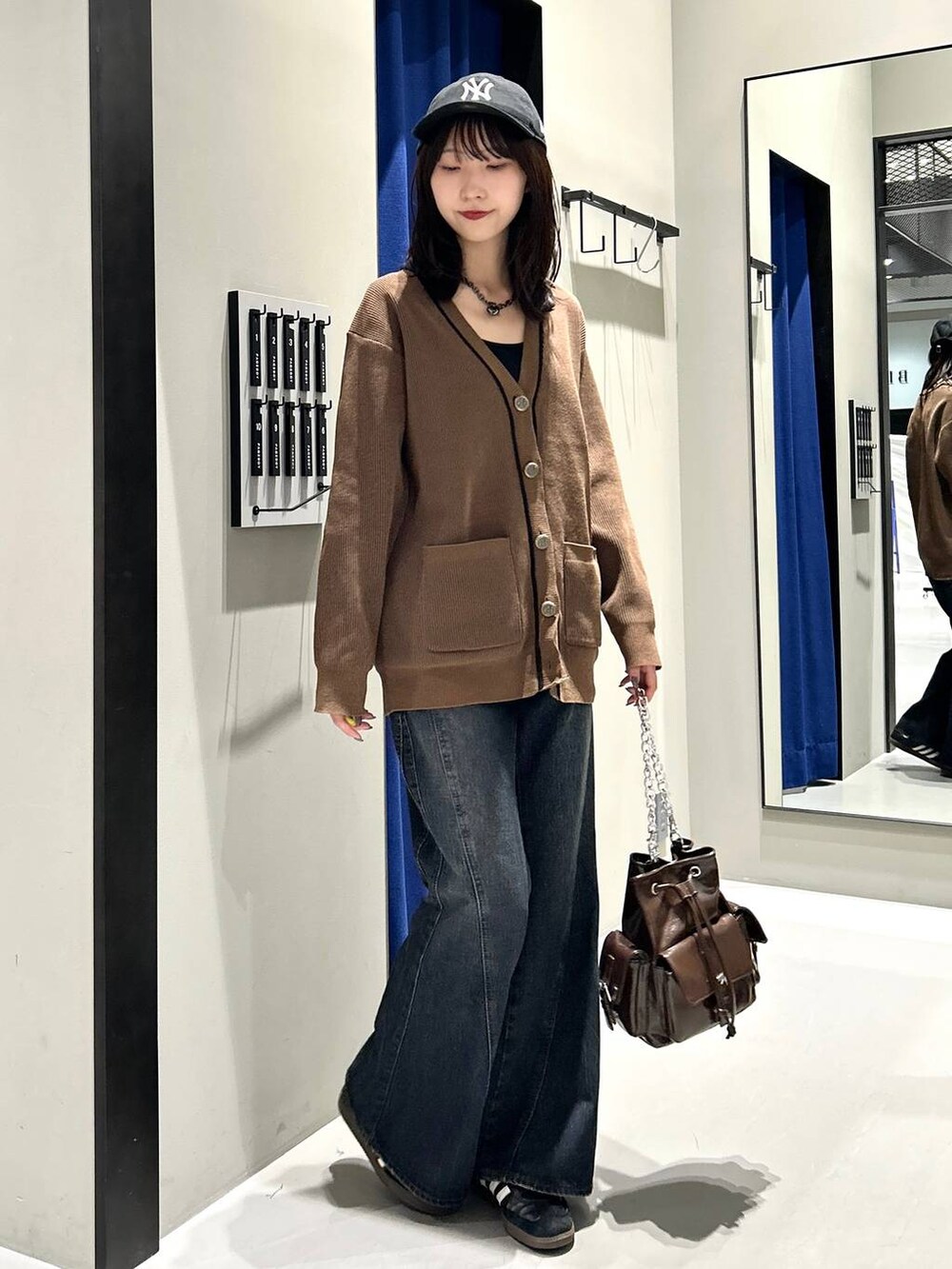 ブラック系のキャミソール、ブルー系のデニムパンツ、ブラウン系のショルダーバッグを着用したレディースの秋コーディネートの2枚目の写真