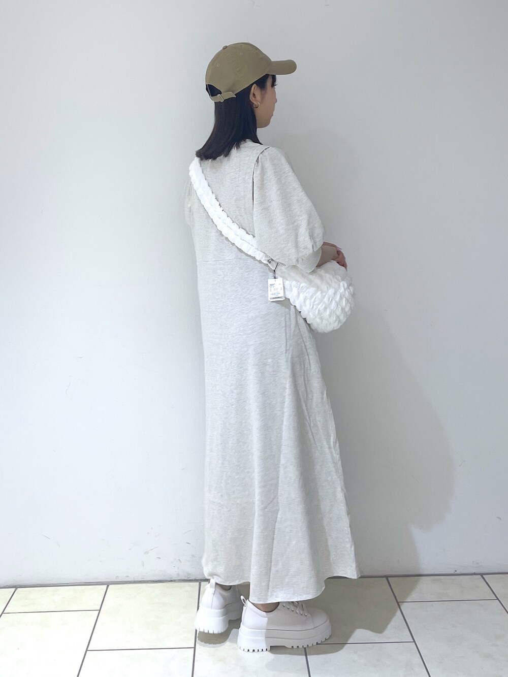 ベージュ系のワンピース、ホワイト系のバッグ、ホワイト系のスニーカーを着用したレディースの春コーディネートの3枚目の写真