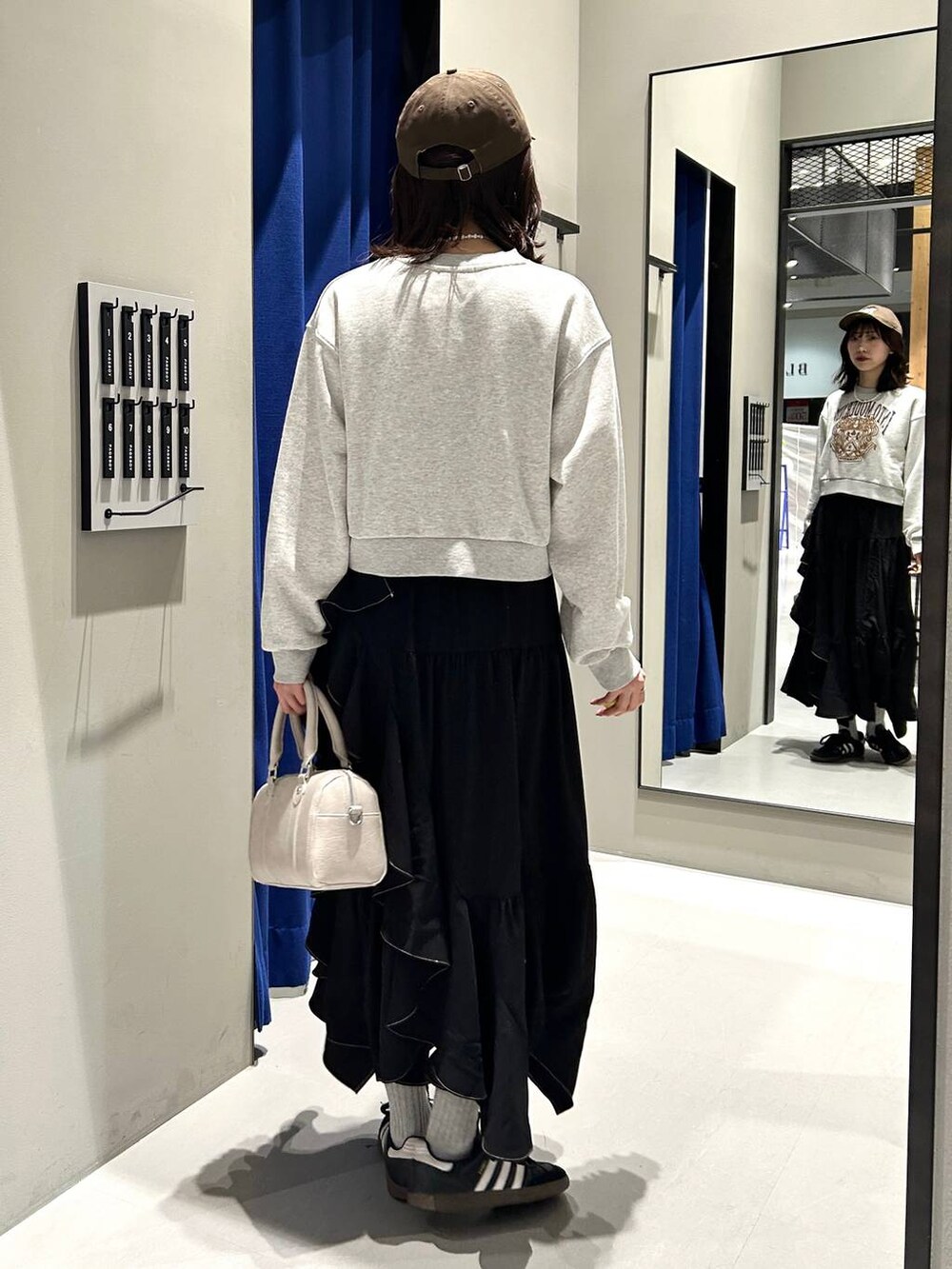 ブラック系のスカート、ホワイト系のボストンバッグ、グレー系のスウェットを着用したレディースの冬コーディネートの8枚目の写真