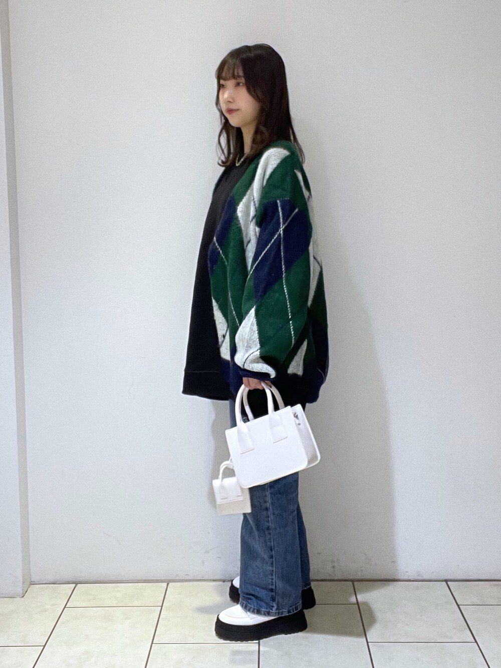 グリーン系のカーディガン/ボレロ、ブラック系のスウェット、ブルー系のデニムパンツを着用したレディースの冬コーディネートの3枚目の写真