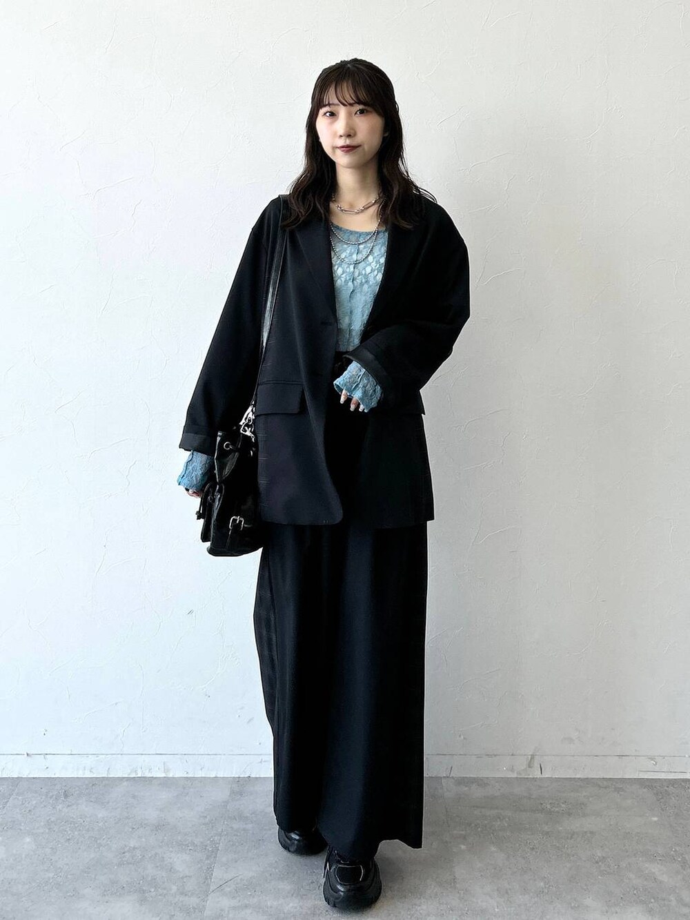 ブラック系のスニーカー、ブラック系のテーラードジャケット、ブラック系のスラックスを着用したレディースの夏コーディネートの4枚目の写真