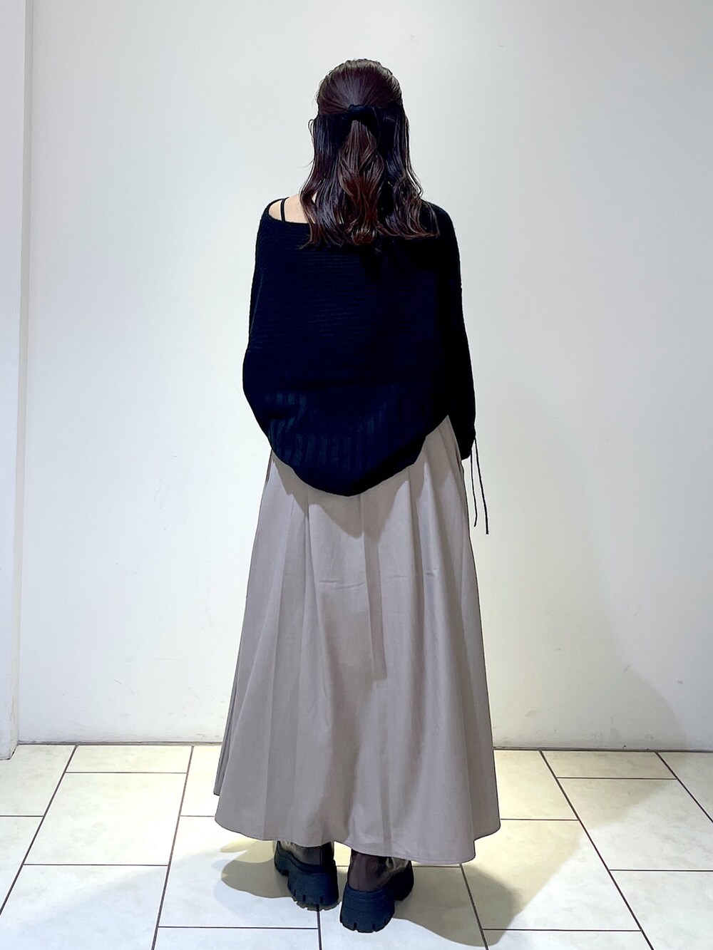 ブラック系のニット/セーター、グレー系のスカート、ブラウン系のブーツを着用したレディースの秋コーディネートの5枚目の写真