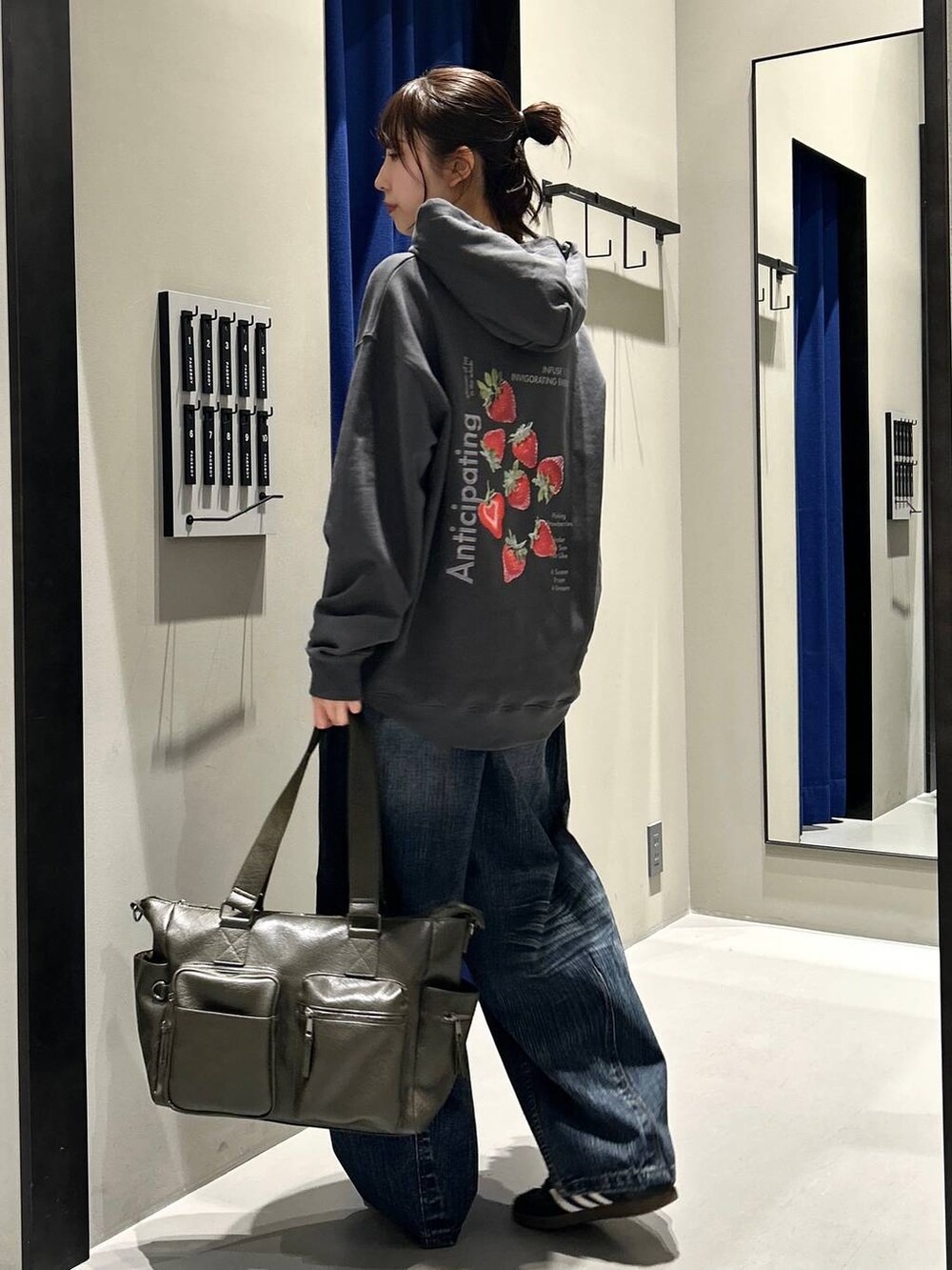 グリーン系のボストンバッグ、グレー系のパーカー、ブルー系のデニムパンツを着用したレディースの秋コーディネートの6枚目の写真