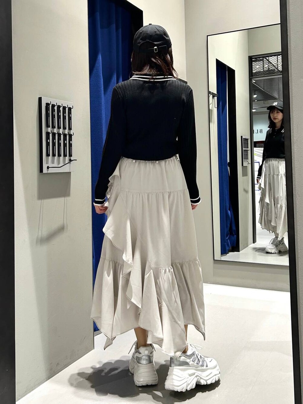 ホワイト系のスニーカー、ベージュ系のスカート、ブラック系のニット/セーターを着用したレディースの冬コーディネートの8枚目の写真