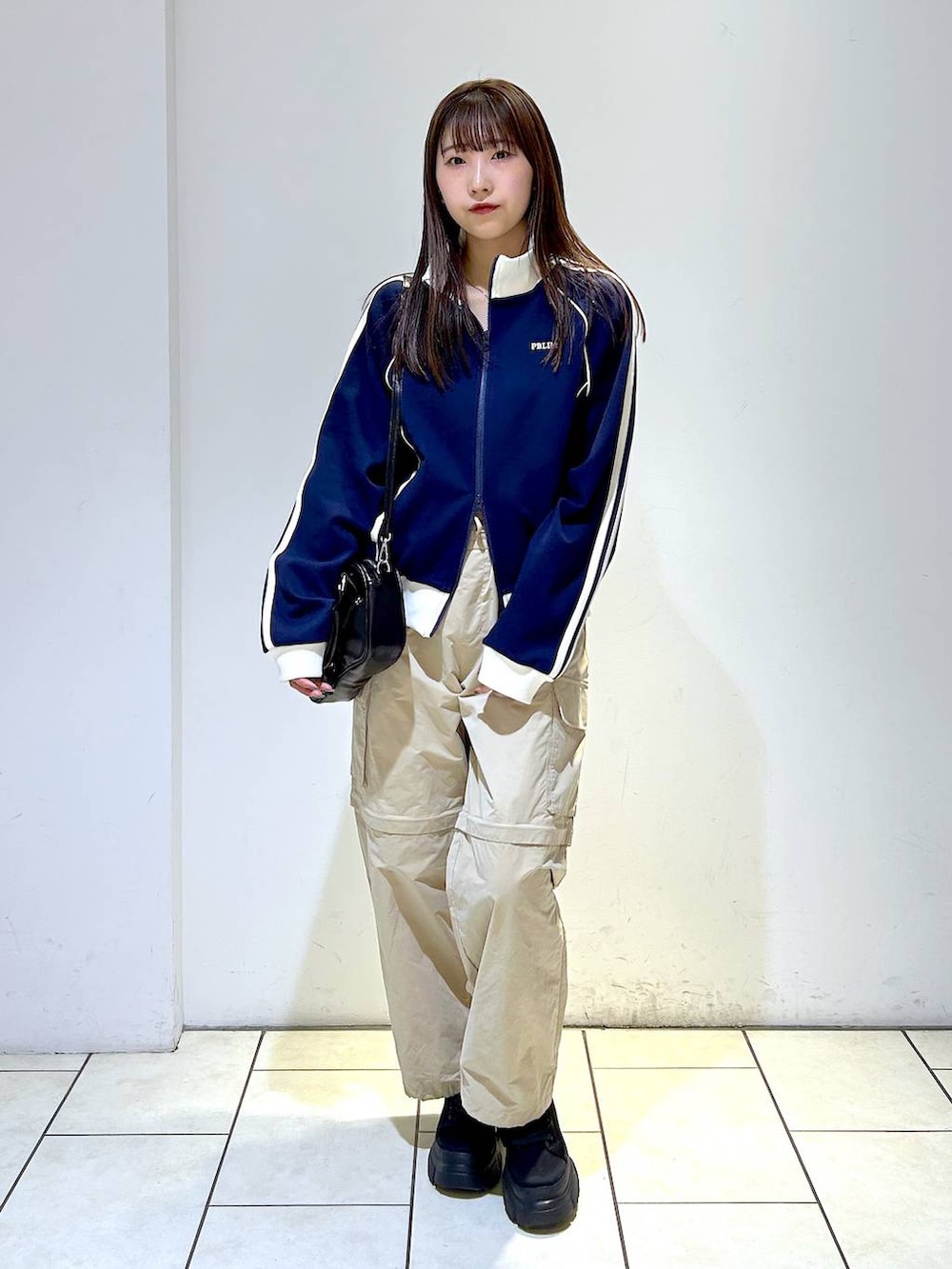 ブルー系のセットアップ、ブラック系のボストンバッグ、ブラック系のブーツを着用したレディースの冬コーディネートの2枚目の写真