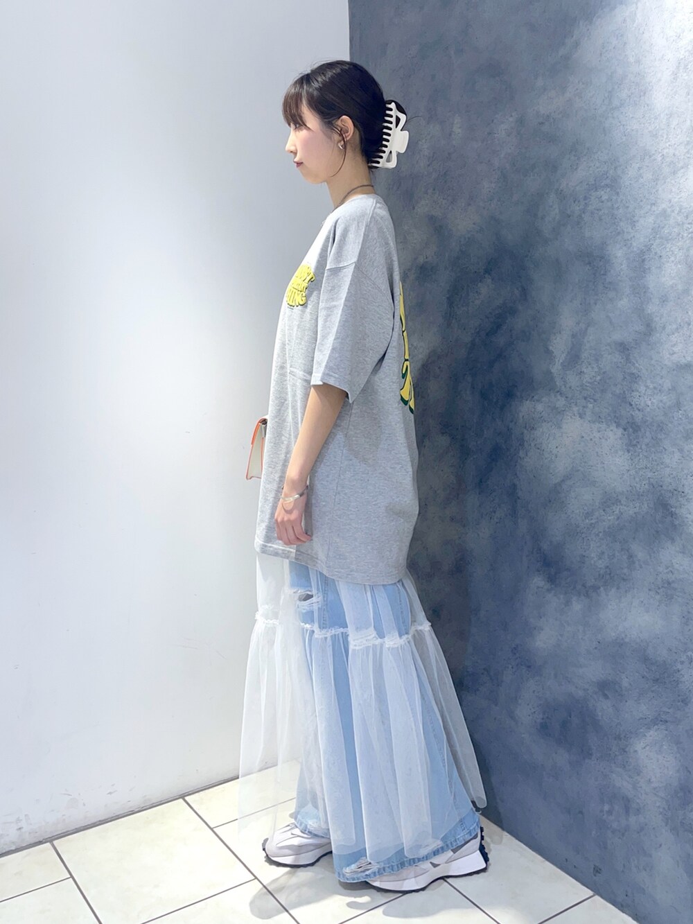 グレー系のTシャツ/カットソー、ホワイト系のワンピース、ブルー系のデニムパンツを着用したレディースの春コーディネートの2枚目の写真