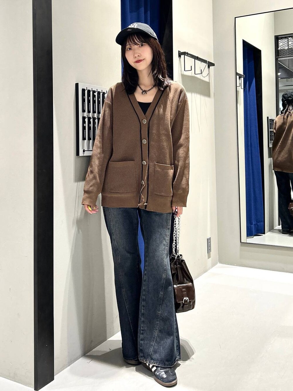 ブラック系のキャミソール、ブルー系のデニムパンツ、ブラウン系のショルダーバッグを着用したレディースの秋コーディネートの3枚目の写真