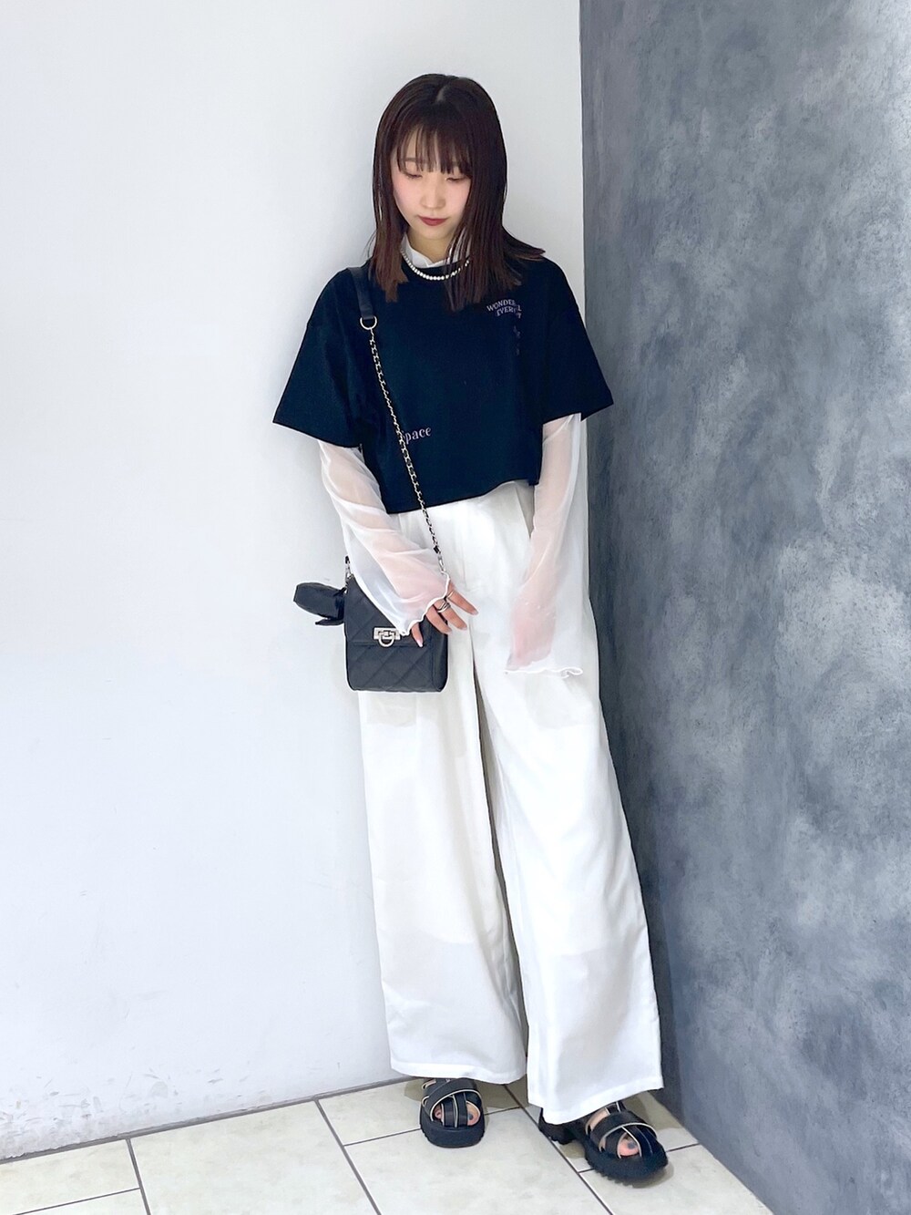 ブラック系のTシャツ/カットソー、ホワイト系のパンツ、ブラック系のサンダルを着用したレディースの春コーディネートの3枚目の写真