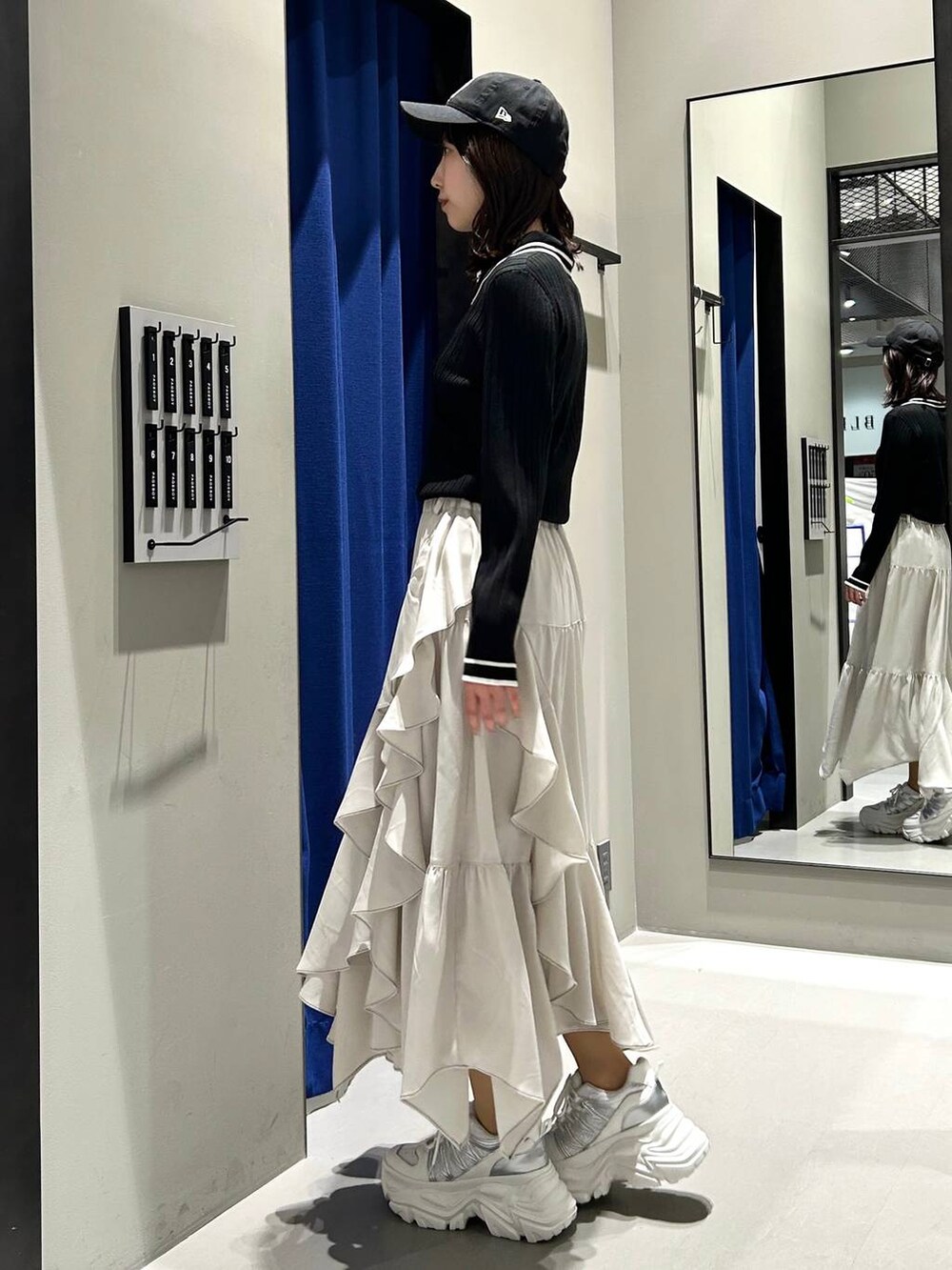 ホワイト系のスニーカー、ベージュ系のスカート、ブラック系のニット/セーターを着用したレディースの冬コーディネートの7枚目の写真