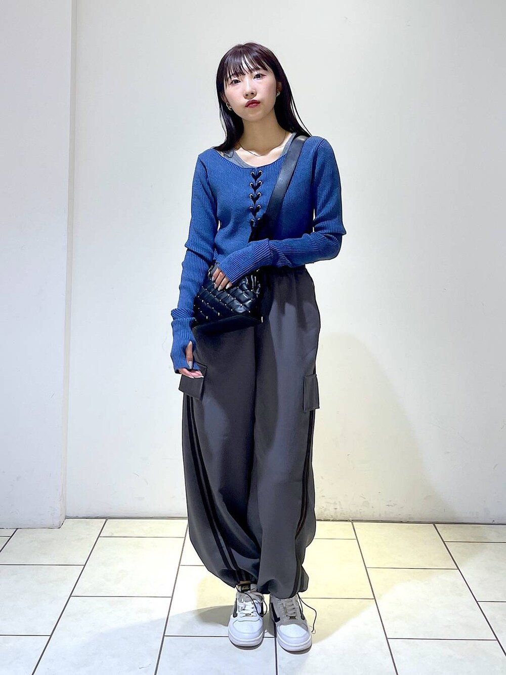 グレー系のその他パンツ、ブラック系のショルダーバッグ、ブルー系のニット/セーターを着用したレディースの冬コーディネートの3枚目の写真