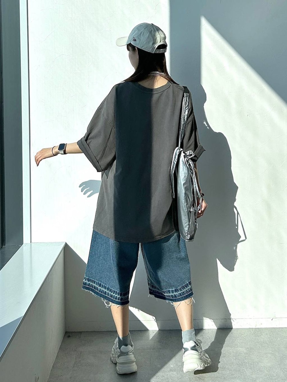 シルバー系のバックパック/リュック、グレー系のTシャツ/カットソー、ブルー系のデニムパンツを着用したレディースの夏コーディネートの6枚目の写真