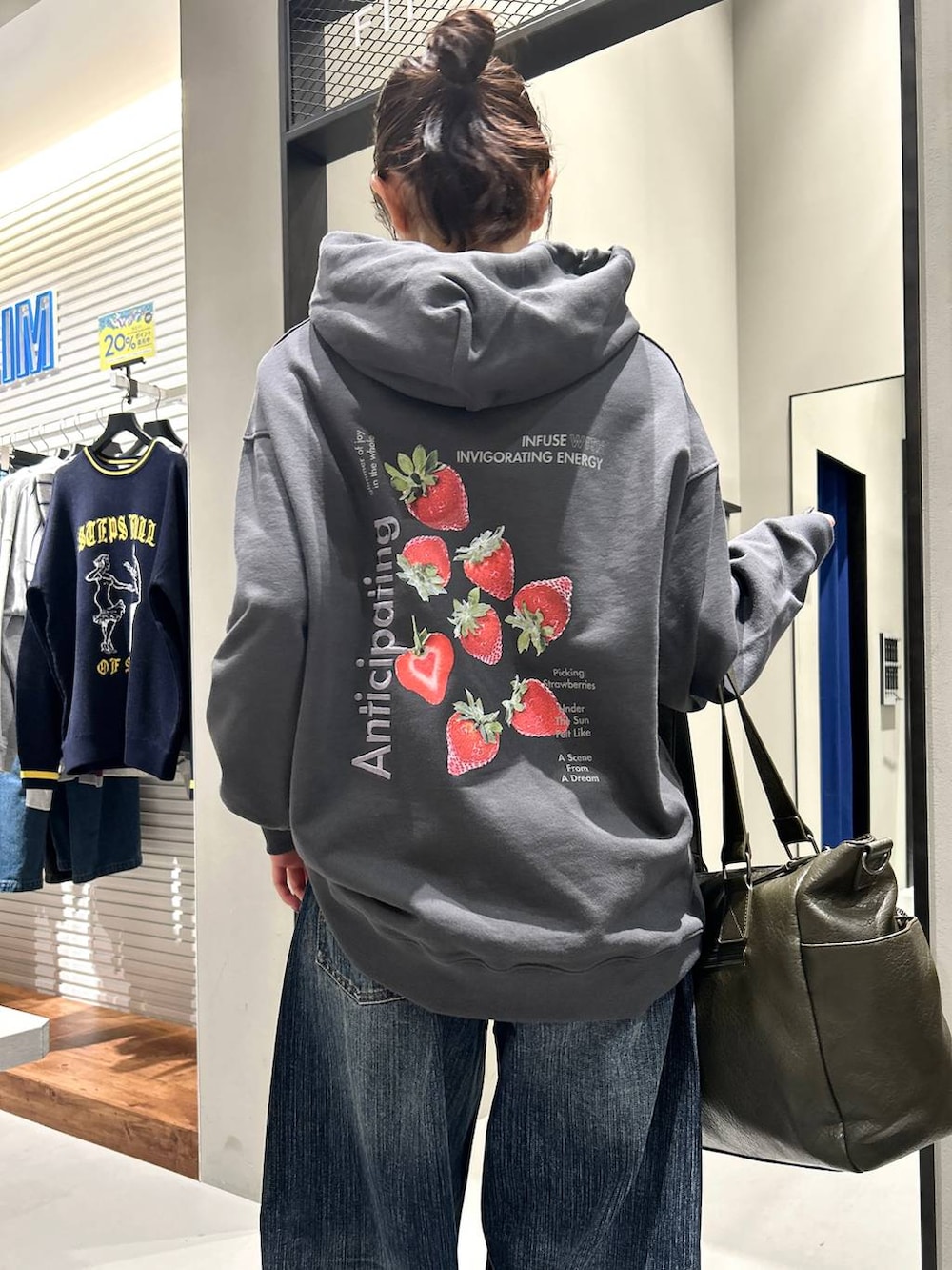 グリーン系のボストンバッグ、グレー系のパーカー、ブルー系のデニムパンツを着用したレディースの秋コーディネートの7枚目の写真