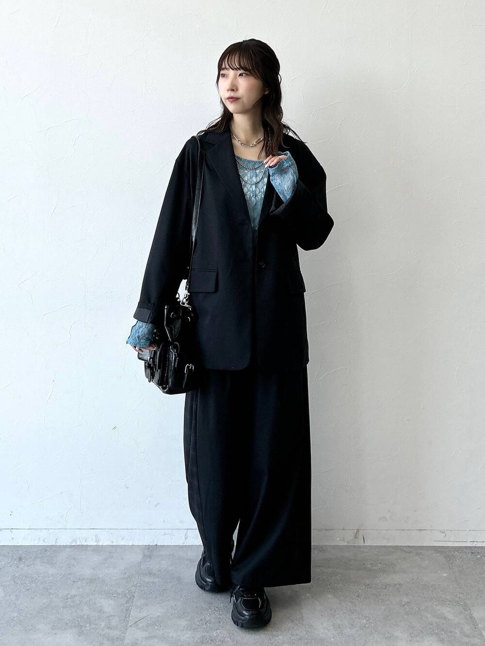 ブラック系のスニーカー、ブラック系のテーラードジャケット、ブラック系のスラックスを着用したレディースの夏コーディネートの5枚目の写真