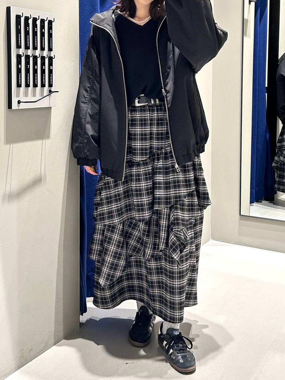 ブラック系のスカート、ブラック系のニット/セーター、ブラック系のナイロンジャケットを着用したレディースの冬コーディネートの3枚目の写真