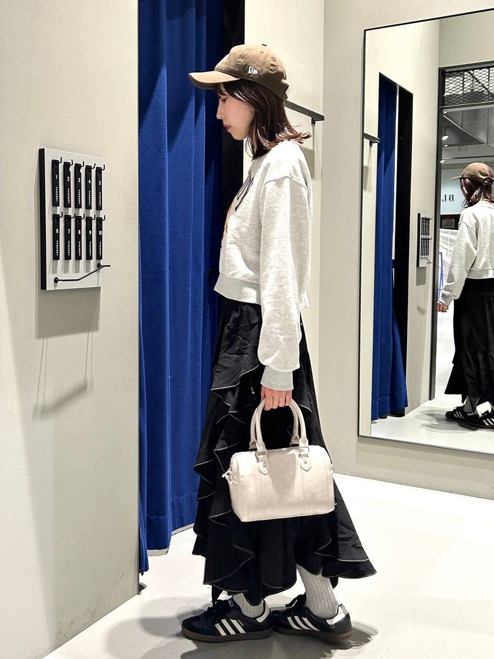 ブラック系のスカート、ホワイト系のボストンバッグ、グレー系のスウェットを着用したレディースの冬コーディネートの7枚目の写真
