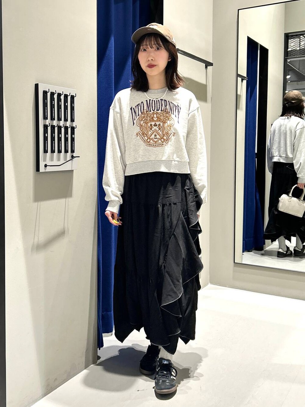 ブラック系のスカート、ホワイト系のボストンバッグ、グレー系のスウェットを着用したレディースの冬コーディネートの4枚目の写真