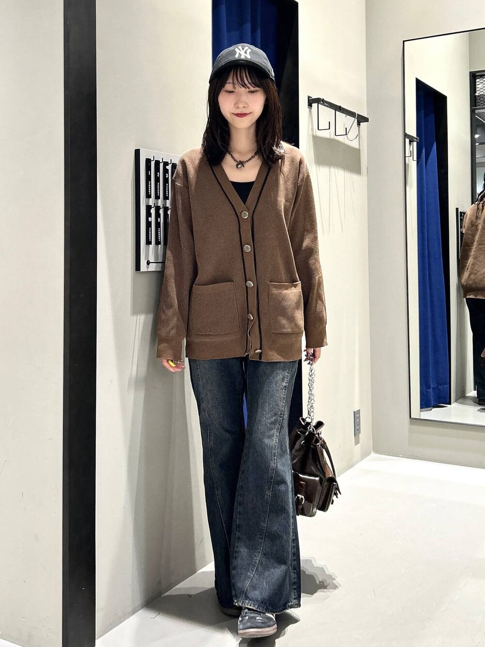 ブラック系のキャミソール、ブルー系のデニムパンツ、ブラウン系のショルダーバッグを着用したレディースの秋コーディネートの5枚目の写真