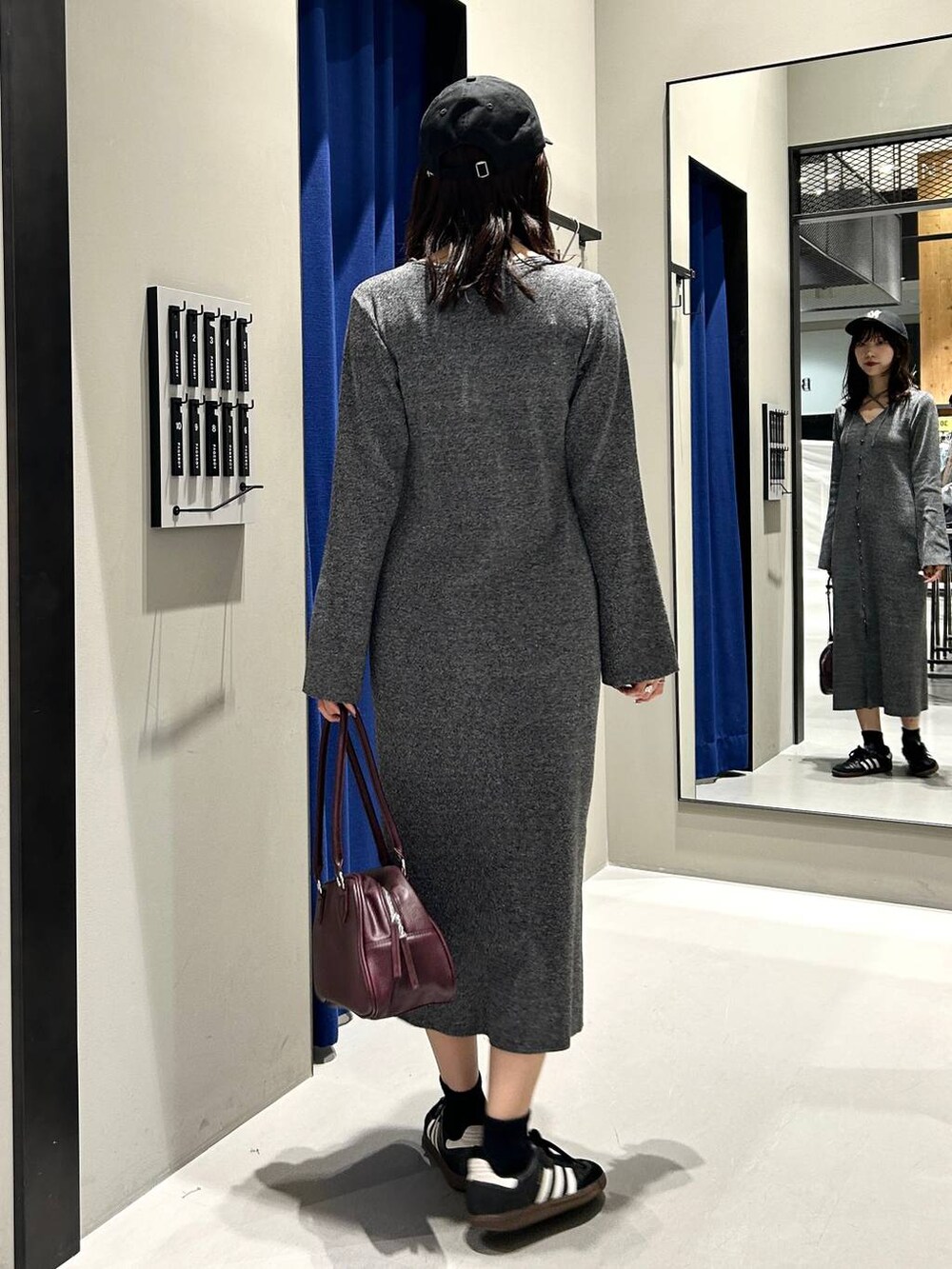 グレー系のワンピース、レッド系のボストンバッグ、ブラック系のキャップを着用したレディースの秋コーディネートの7枚目の写真