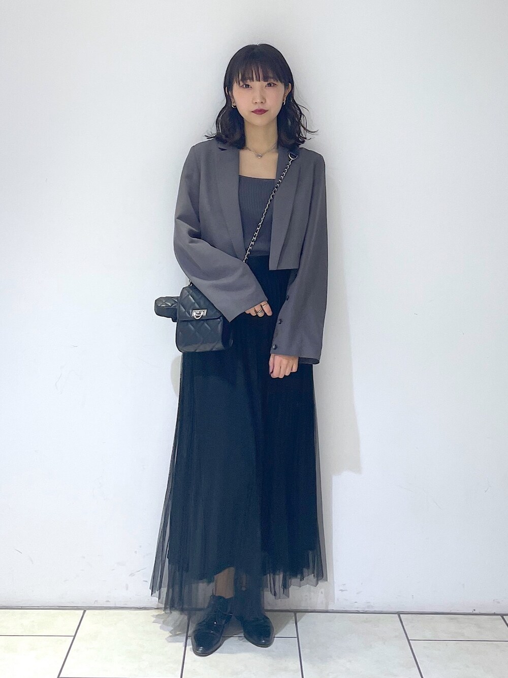 グレー系のテーラードジャケット、グレー系のタンクトップ、ブラック系のスカートを着用したレディースの春コーディネートの2枚目の写真