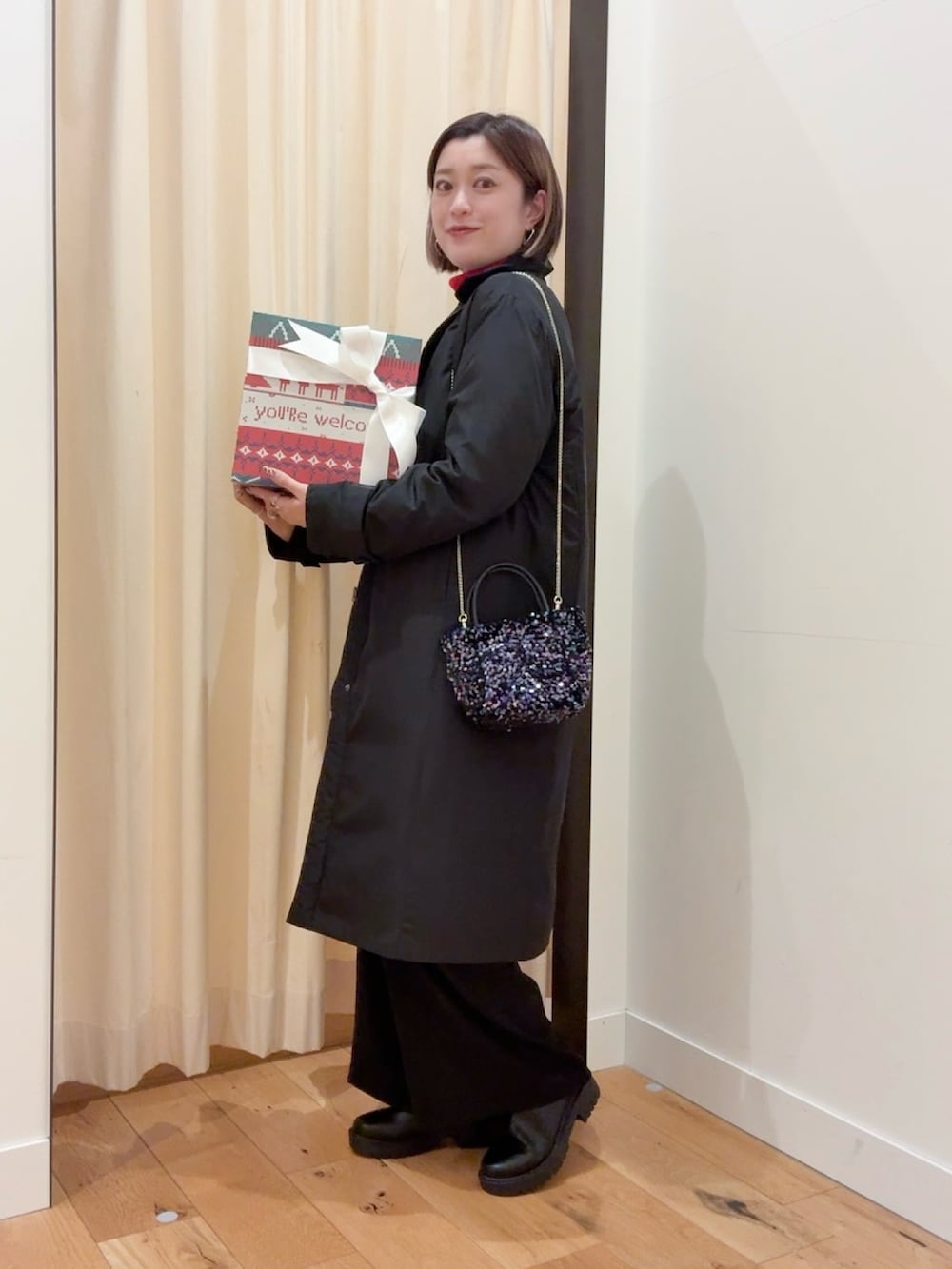 レッド系のニット/セーター、ブラック系のダウンジャケット/コート、ブラック系のサロペット/オーバーオールを着用したレディースの秋コーディネートの7枚目の写真