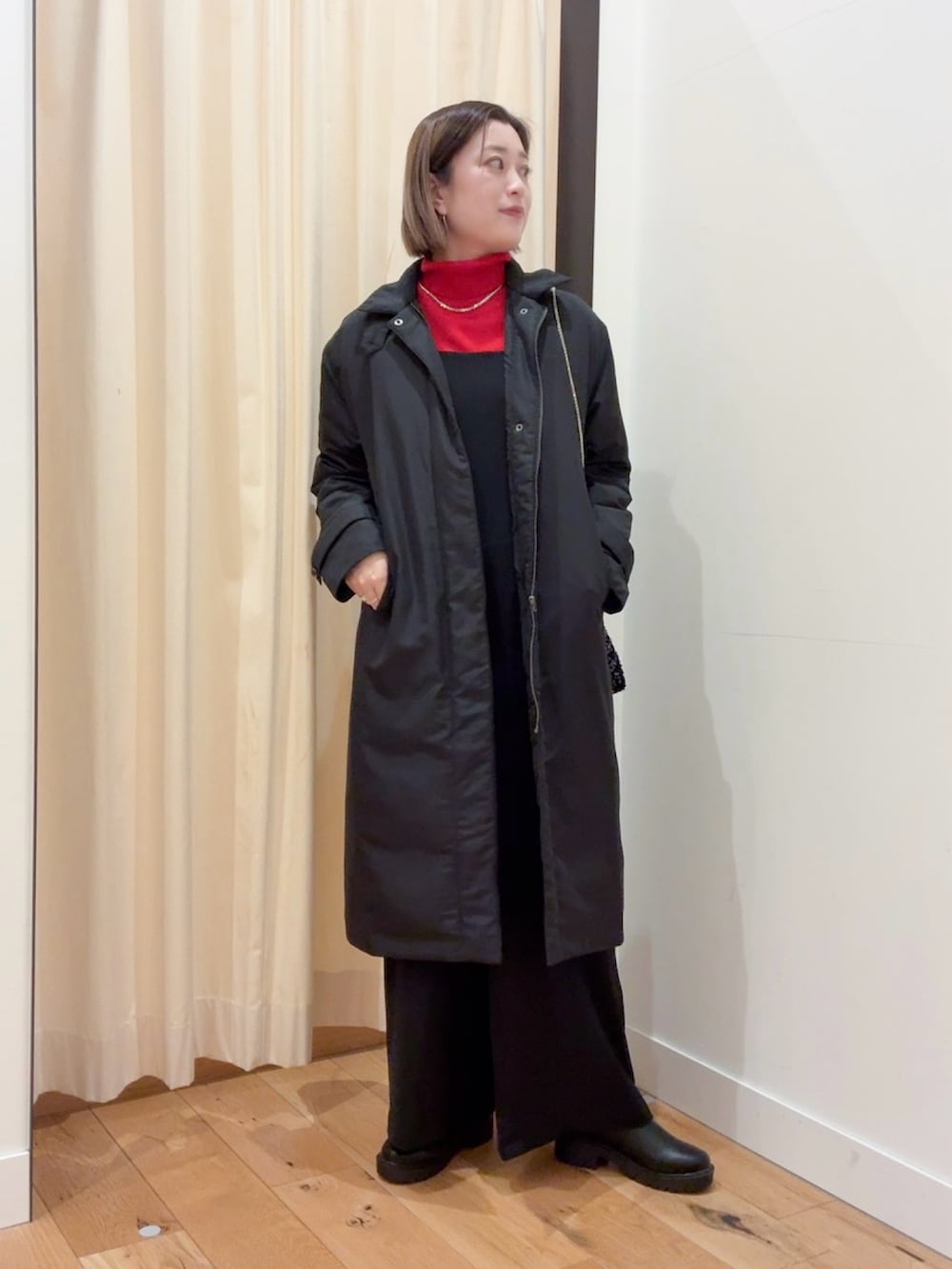 レッド系のニット/セーター、ブラック系のダウンジャケット/コート、ブラック系のサロペット/オーバーオールを着用したレディースの秋コーディネートの3枚目の写真