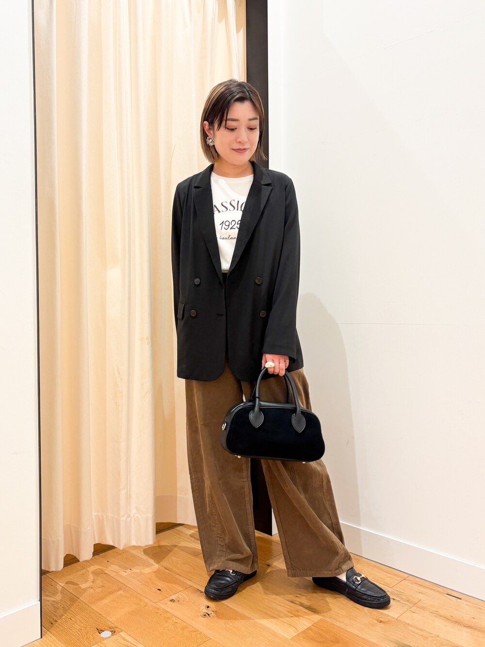 ブラック系のその他アウター、ホワイト系のTシャツ/カットソー、ブラック系のショルダーバッグを着用したレディースの秋コーディネートの2枚目の写真