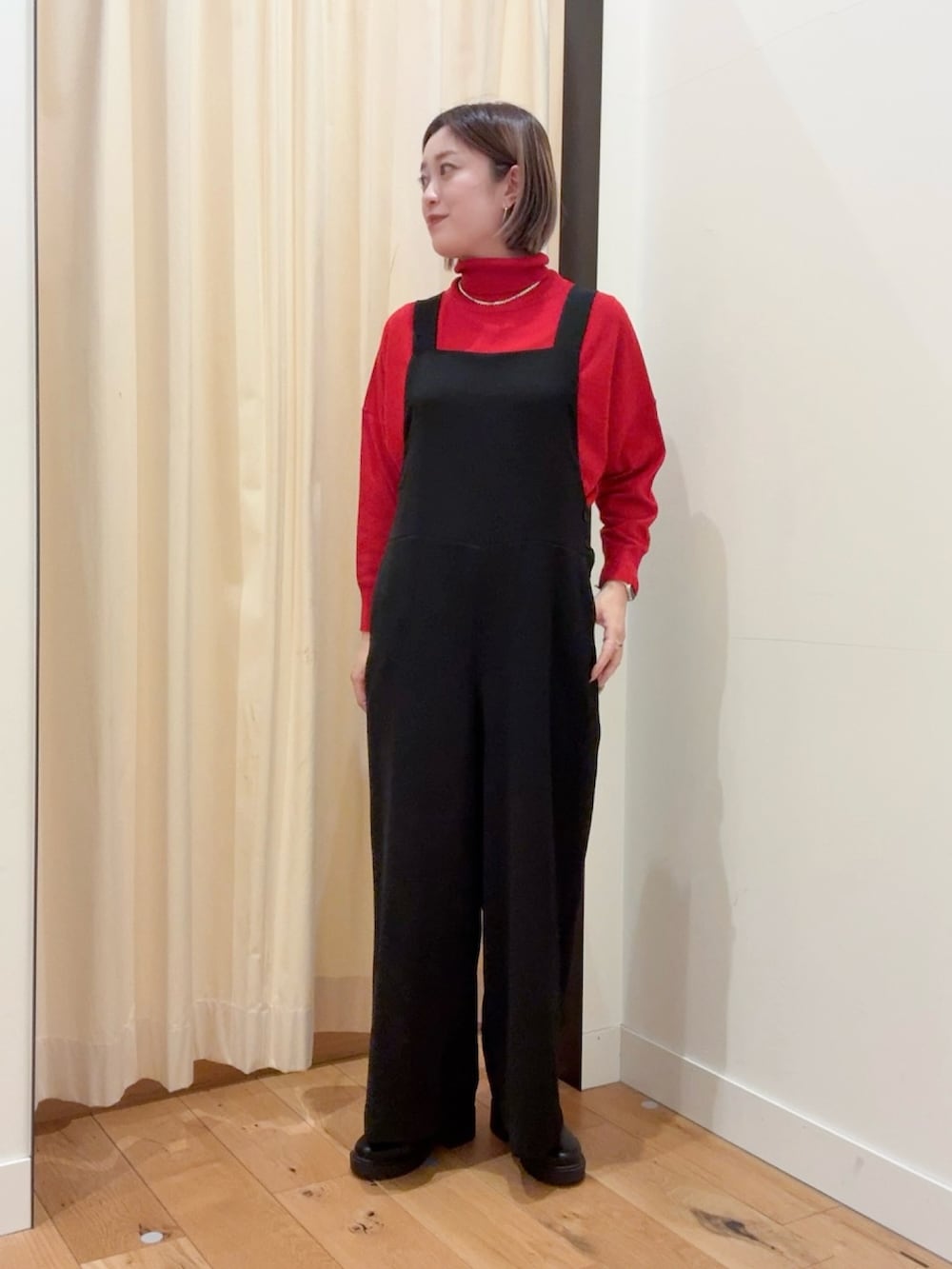 レッド系のニット/セーター、ブラック系のダウンジャケット/コート、ブラック系のサロペット/オーバーオールを着用したレディースの秋コーディネートの6枚目の写真