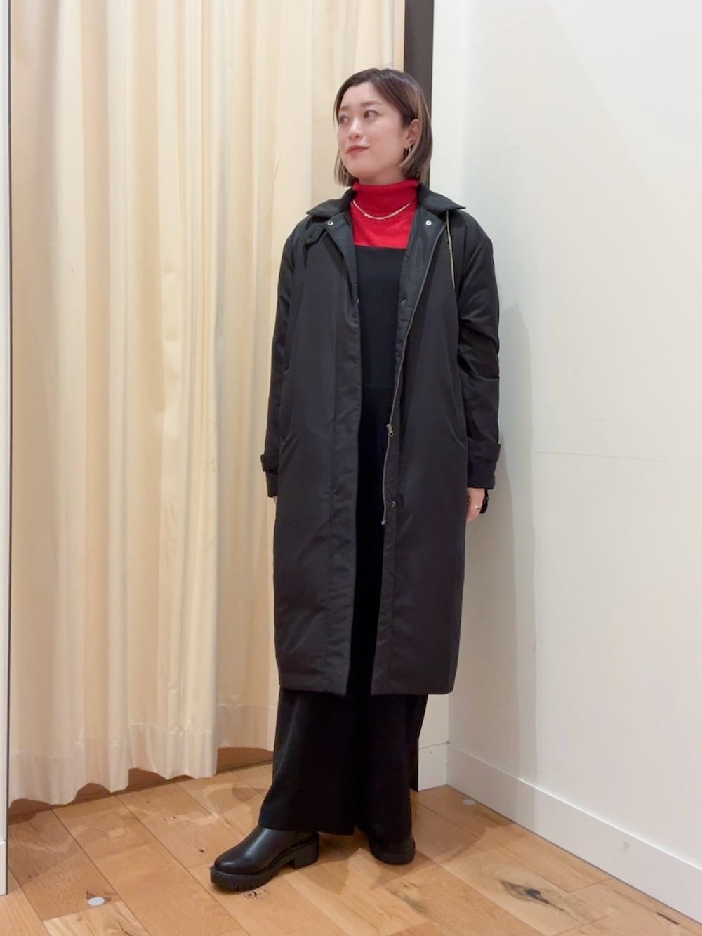 レッド系のニット/セーター、ブラック系のダウンジャケット/コート、ブラック系のサロペット/オーバーオールを着用したレディースの秋コーディネートの4枚目の写真