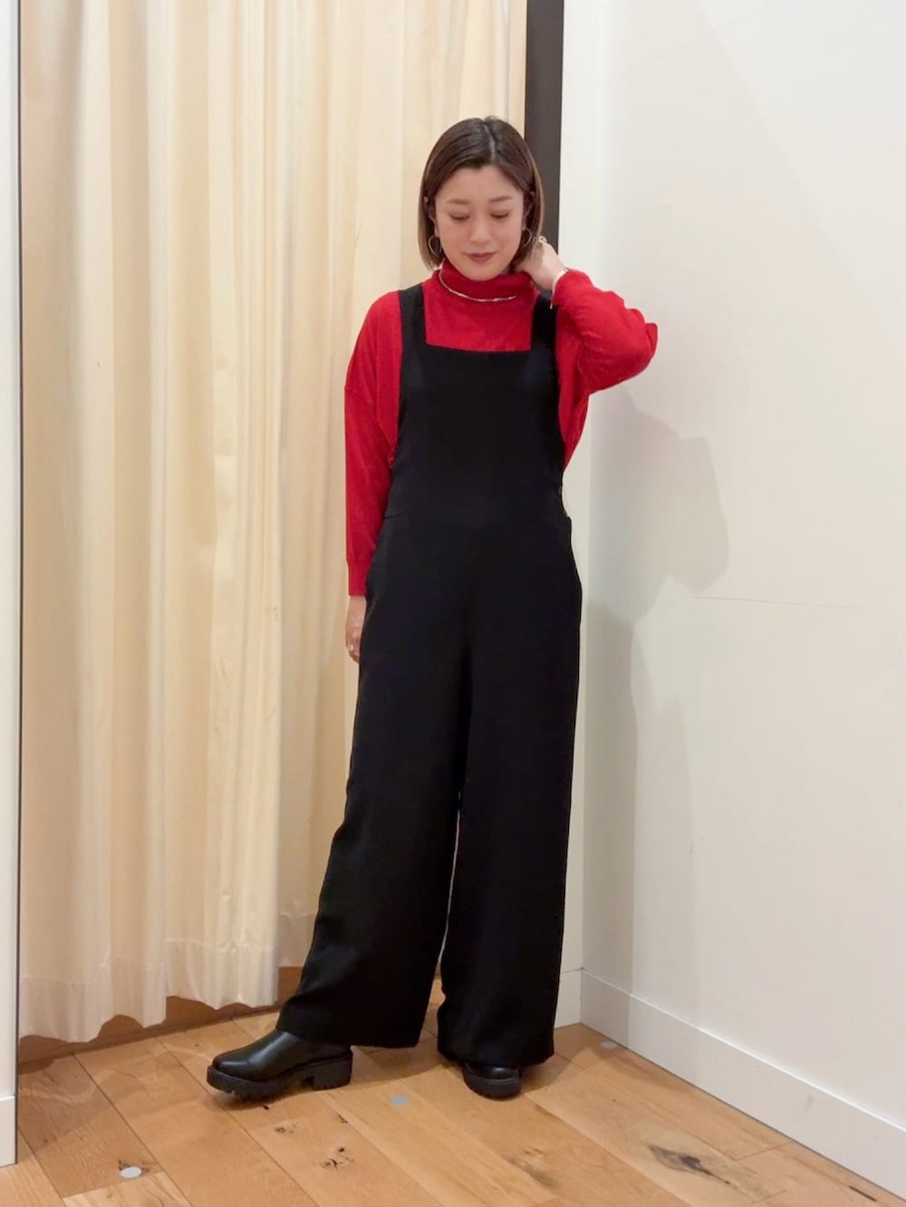 レッド系のニット/セーター、ブラック系のダウンジャケット/コート、ブラック系のサロペット/オーバーオールを着用したレディースの秋コーディネートの5枚目の写真