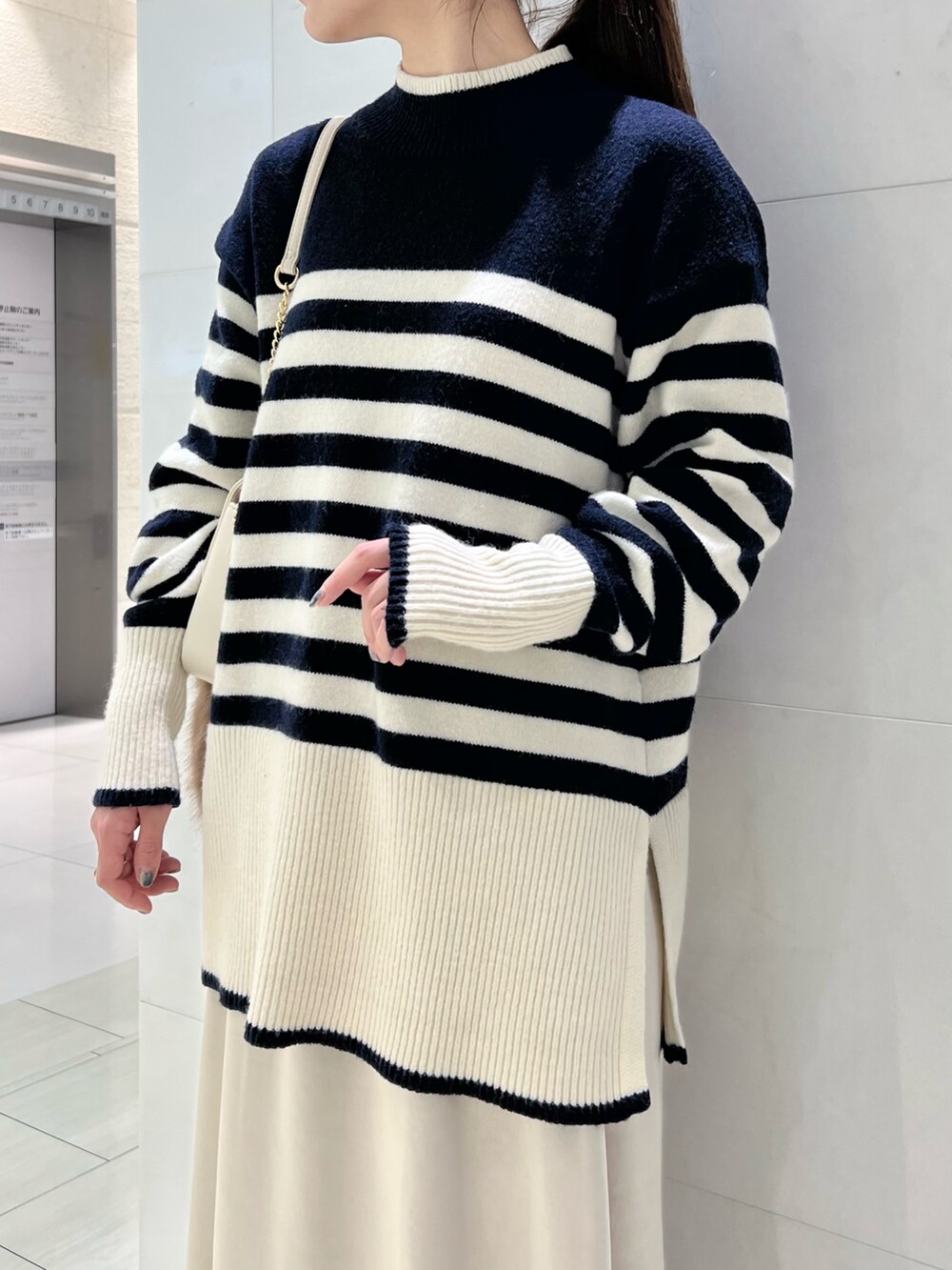 ブルー系のニット/セーター、グレー系のスカート、ホワイト系のブーツを着用したレディースの冬コーディネートの2枚目の写真