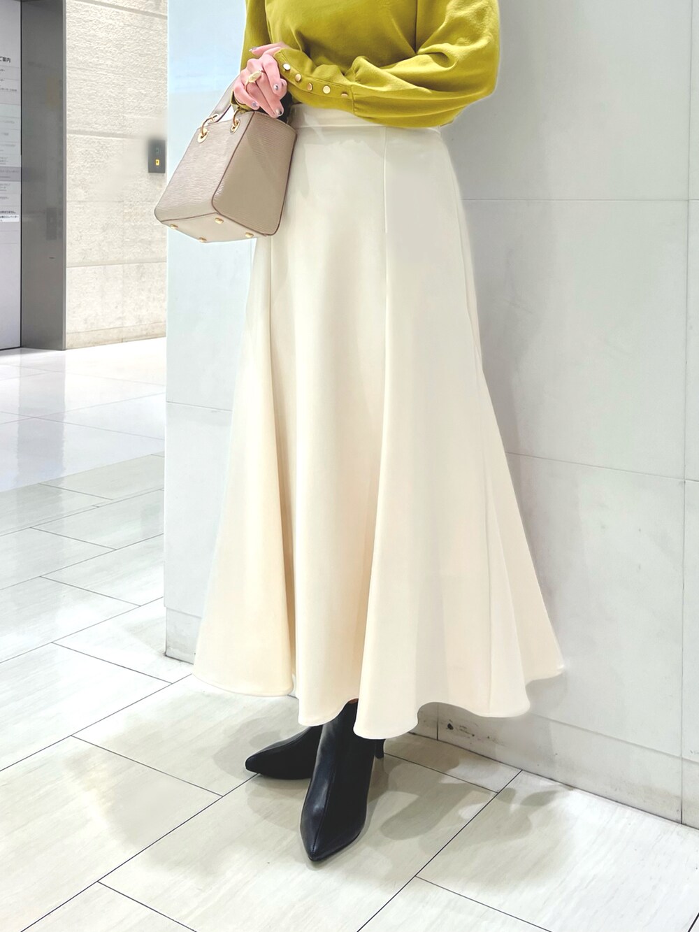 ブラック系のブーツ、ベージュ系のチェスターコート、イエロー系のニット/セーターを着用したレディースの秋コーディネートの4枚目の写真