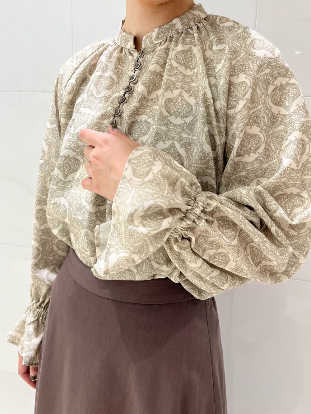 ベージュ系のシャツ/ブラウス、ブラウン系のスカート、ホワイト系のブーツを着用したレディースの秋コーディネートの3枚目の写真