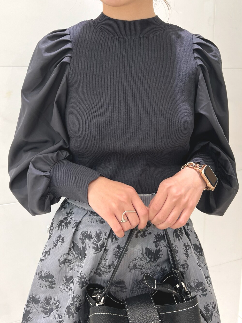 グレー系のニット/セーター、ブラック系のハンドバッグ、ブラック系のパンプスを着用したレディースの秋コーディネートの3枚目の写真