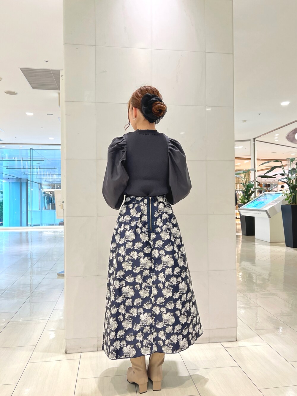 グレー系のニット/セーター、ブルー系のスカート、ベージュ系のハンドバッグを着用したレディースの秋コーディネートの2枚目の写真