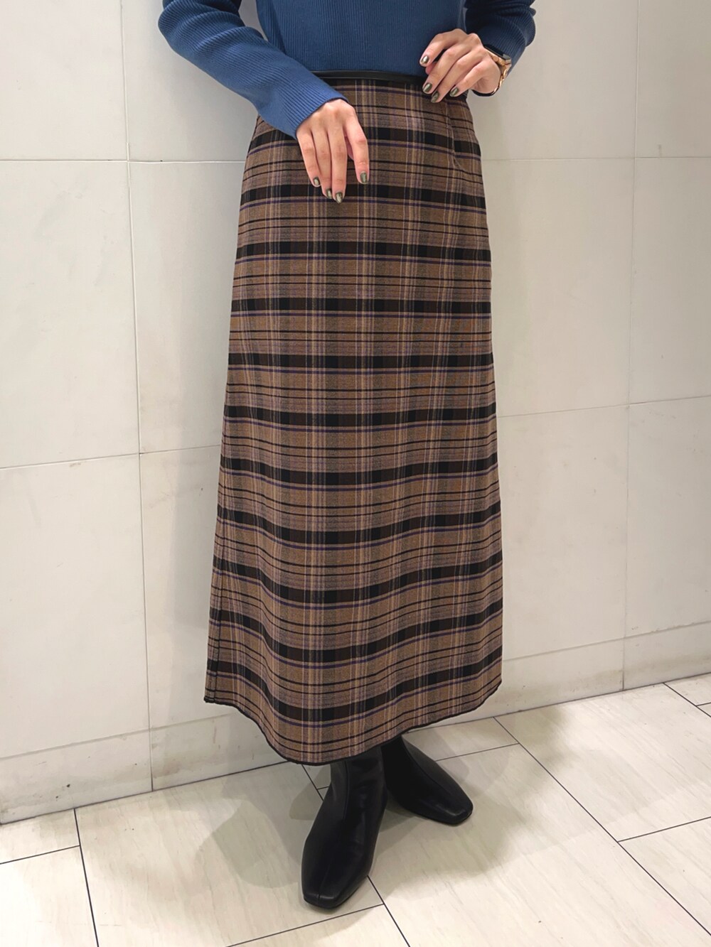 ブルー系のニット/セーター、ブラウン系のスカート、ブラック系のブーツを着用したレディースの秋コーディネートの3枚目の写真