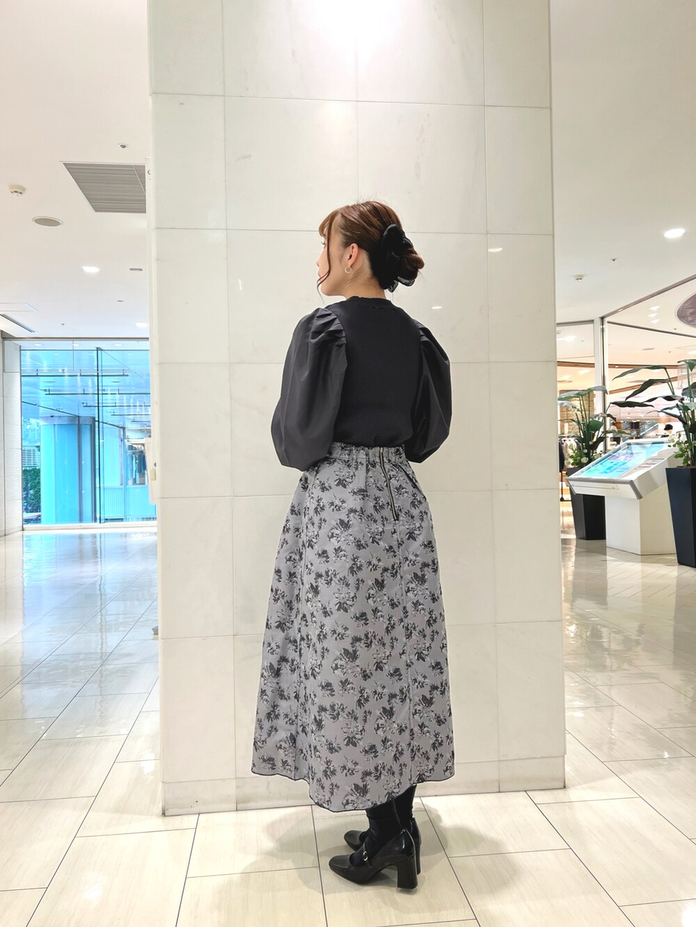 グレー系のニット/セーター、ブラック系のハンドバッグ、ブラック系のパンプスを着用したレディースの秋コーディネートの2枚目の写真