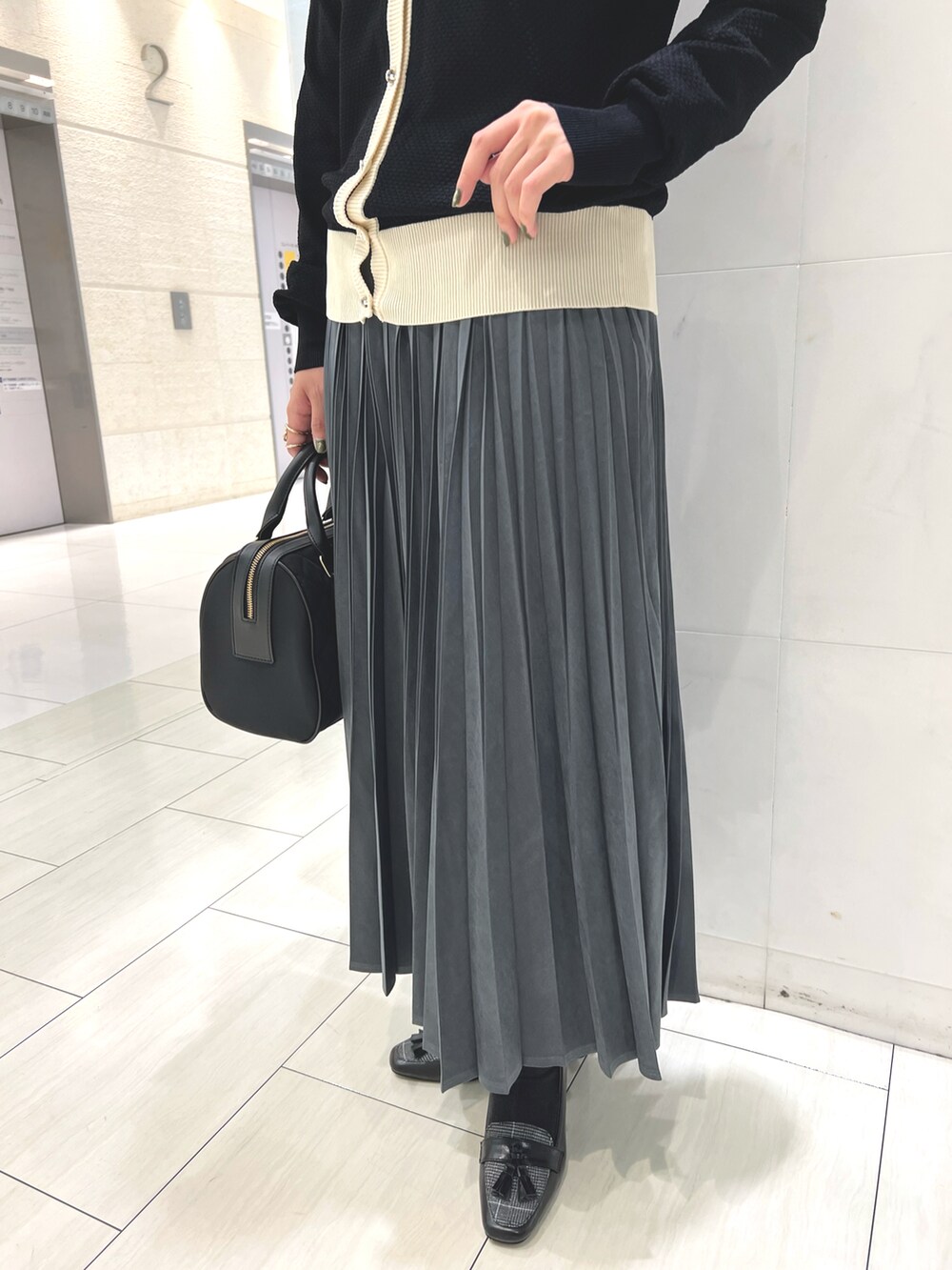 ホワイト系のTシャツ/カットソー、ブラック系のカーディガン/ボレロ、ホワイト系のスカートを着用したレディースの秋コーディネートの3枚目の写真