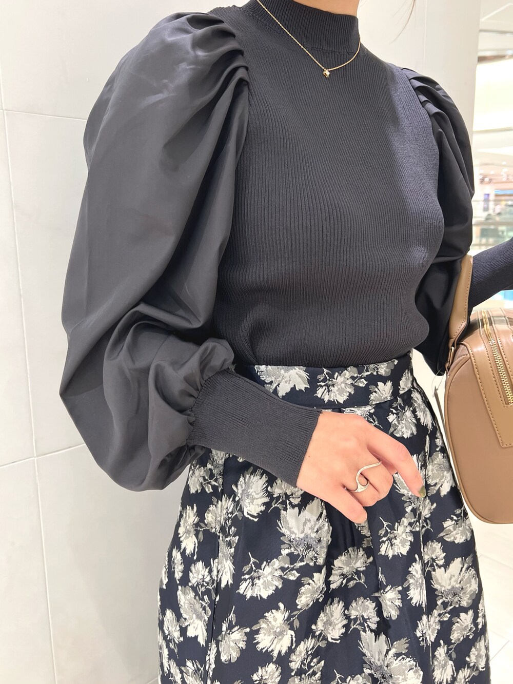 グレー系のニット/セーター、ブルー系のスカート、ベージュ系のハンドバッグを着用したレディースの秋コーディネートの3枚目の写真