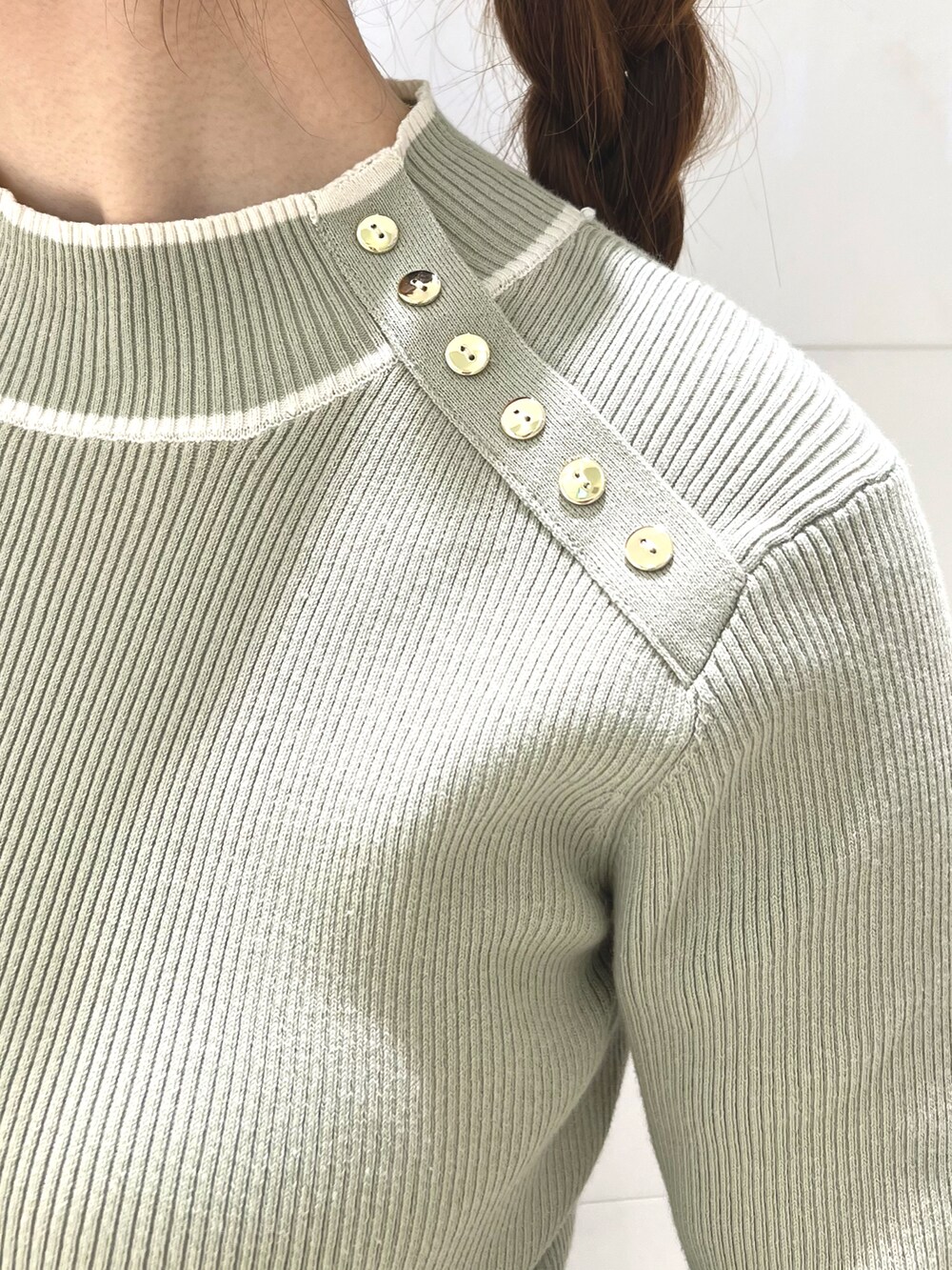 グリーン系のニット/セーター、ブルー系のスカート、ブラウン系のパンプスを着用したレディースの秋コーディネートの2枚目の写真