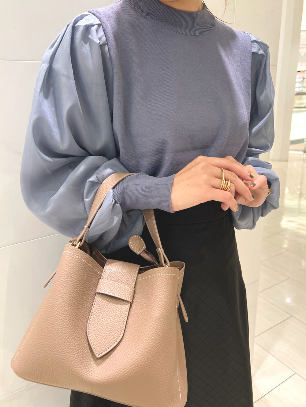 ブルー系のニット/セーター、ベージュ系のハンドバッグ、ブラック系のスカートを着用したレディースの秋コーディネートの2枚目の写真