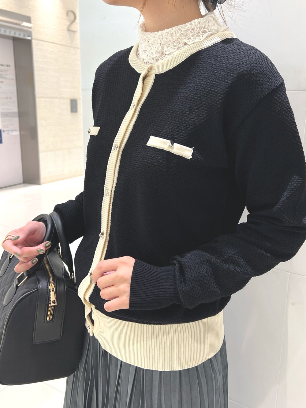 ホワイト系のTシャツ/カットソー、ブラック系のカーディガン/ボレロ、ホワイト系のスカートを着用したレディースの秋コーディネートの2枚目の写真