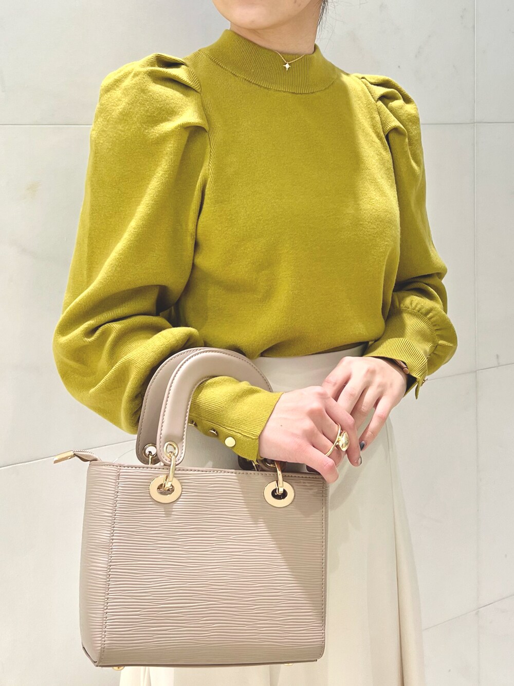 ブラック系のブーツ、ベージュ系のチェスターコート、イエロー系のニット/セーターを着用したレディースの秋コーディネートの3枚目の写真