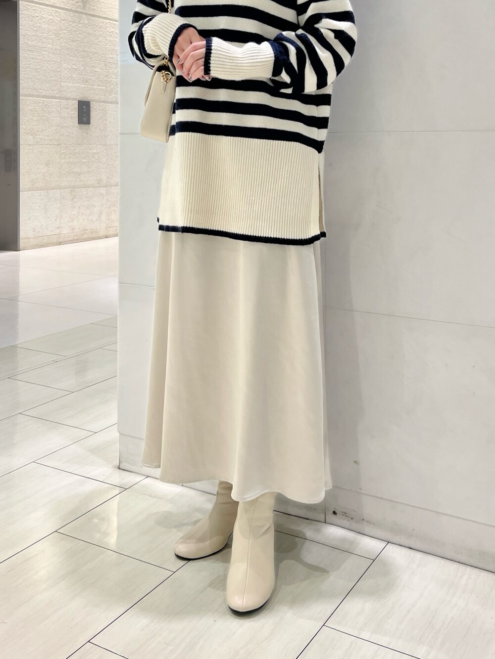 ブルー系のニット/セーター、グレー系のスカート、ホワイト系のブーツを着用したレディースの冬コーディネートの3枚目の写真