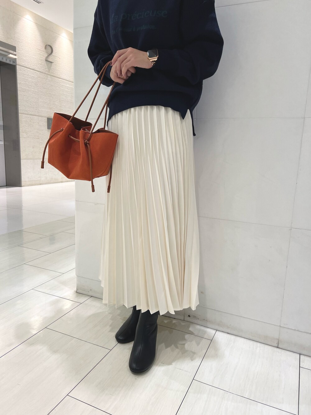ブルー系のニット/セーター、ホワイト系のスカート、オレンジ系のハンドバッグを着用したレディースの秋コーディネートの3枚目の写真