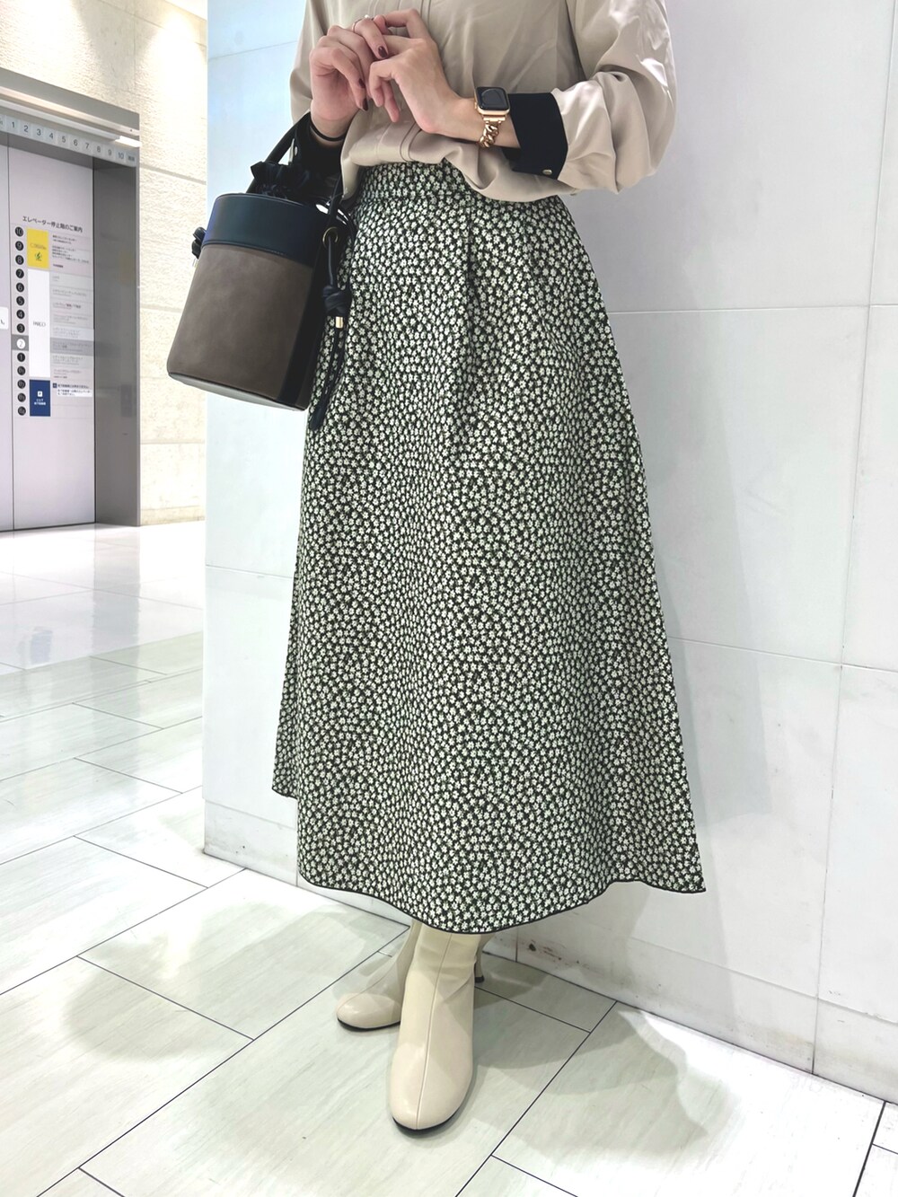 ベージュ系のシャツ/ブラウス、ブラック系のスカート、ブラウン系のハンドバッグを着用したレディースの秋コーディネートの3枚目の写真