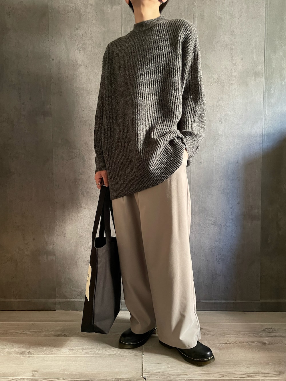 グレー系のスラックス、ブラック系のドレスシューズ、グレー系のニット/セーターを着用したメンズの秋コーディネートの2枚目の写真