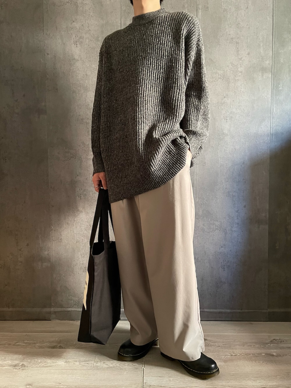 グレー系のスラックス、ブラック系のドレスシューズ、グレー系のニット/セーターを着用したメンズの秋コーディネートの3枚目の写真