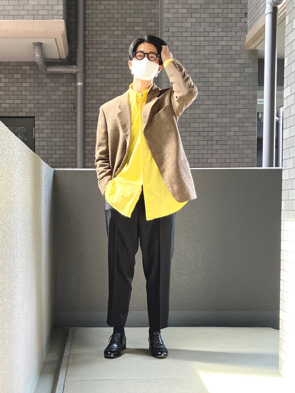 ブラック系のスラックス、ブラック系のドレスシューズ、イエロー系のシャツ/ブラウスを着用したメンズの春コーディネートの3枚目の写真